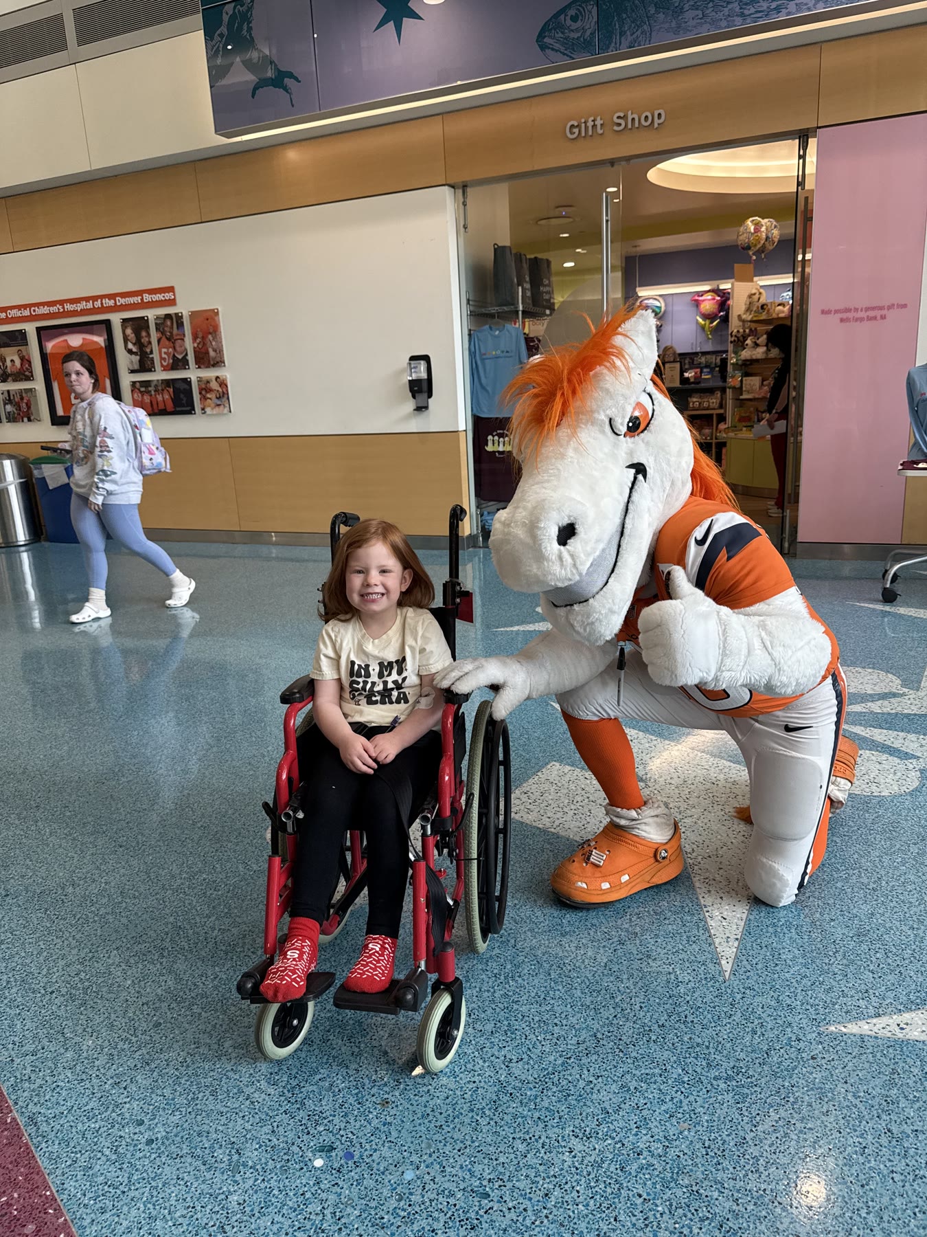 Gracie Jennings smiling with the Denver Broncos mascot at Children's Hospital Colorado